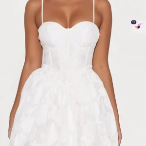 Vit kortklänning med smala axelband - Supersöt vit kortklänning med smala axelband och markerad byst. Kjolen är fluffig och har en lätt volang-effekt. Perfekt för sommarens och students alla tillfällen när du vill känna dig extra fin. Alldrig använd pågrund av för liten storlek. Skickas direkt.