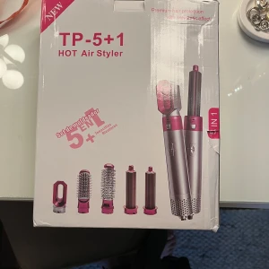TP-5+1 Hot Air Styler med flera tillbehör - Multifunktionell hårstyler i vitt och guld med fem utbytbara tillbehör: rundborste, volymborste, två locktillbehör och munstycke. Perfekt för att skapa olika frisyrer med varmluft. Ergonomisk design och enkel att använda. Aldrig använd då jag föredrar att ha mitt naturliga hår