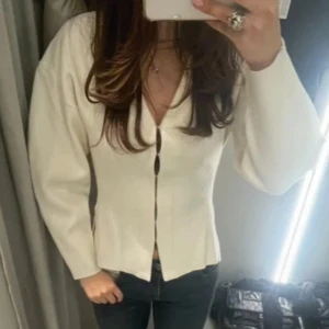 Vit kofta med knappar - Säljer en stilren vit kofta med v-ringning och knappar framtill. Tröjan har lång ärm och en figurnära passform som ger en snygg siluett. Perfekt att styla med jeans eller kjol för en trendig look. Köpt för 380kr. använd den typ 3 gånger🩷🩷
