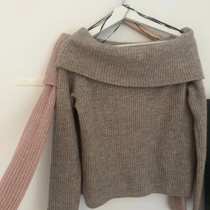 Beige ribbad offshouldertröja från H&M - Säljer en beige och en rosa ribbad tröja från H&M med bred offshoulderkrage. Tröjan har lång ärm och är stickad i mjukt material. Båda för 200.