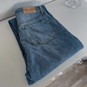 Blå högmidjade jeans 💙 - Ett par blå högmidjade jeans från NA-KD i storlek 36 som köptes secondhand men som tyvärr var för små så har aldrig kommit till användning. Nypris 500kr! FÖRST TILL KVARN!💙(BUNDLERABATT VID KÖP AV FLER ARTIKLAR, KIKA MIN PROFIL!)