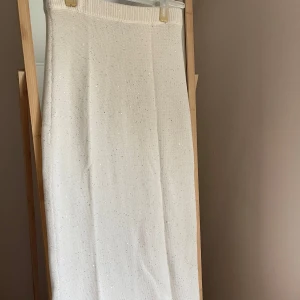Vit stickad långkjol med glitter - Säljer en vit stickad långkjol med diskreta glittriga detaljer. Kjolen har en bred resår i midjan och är rak i modellen. Aldrig använd prislapp borttagen 