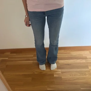 Blå bootcut jeans med paljetter - Snygga blå jeans med bootcut passform med paljetter på bakfickorna. Jeansen har dubbla knappar i midjan och klassisk fem fickors design. Några paljetter har trillat av. Använda max 10ggr! Se bilderna för midjemått och innerbens längd. Ganska stretchigt i midjan så de är 31-38cm i midjan. Midwaist. Passar mig som är 154💕läs bio!