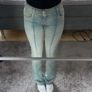 Lågmidjade jeans - Säljer ett par ljusblå lågmidjade jeansbyxor från Bershka med bootcut och låg midja. Byxorna har två knappar framtill, klassiska fickor och markerade sömmar längs benen. Perfekta för en avslappnad och trendig look.