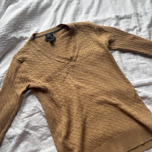 Stickad tröja från Tommy Hilfiger - Säljer en beige v-ringad stickad tröja från Tommy Hilfiger i 100% bomull. Den är nästintill oanvänd eftersom den är lite för stor på mig därav är tröjan i bra skick, skriv för fler bilder💗