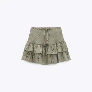 Olivgrön volangkjol med broderade detaljer - Supersöt olivgrön kjol med volanger och broderade detaljer. Kjolen har knyt i midjan och är perfekt för dig som gillar en feminin och trendig stil. Passar till både sneakers och sandaler.