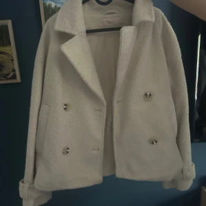Beige teddyjacka med knappar från Nelly  - En fin teddyjacka från Nelly för 200kr knappt använd! Storlek M.