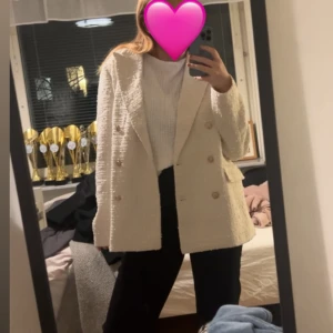 Vit tweed kavaj med guldknappar - Säljer en stilren vit kavaj i tweed med dubbelknäppning och guldiga knappar. Kavajen har klassisk krage, två fickor framtill och är helfodrad. Perfekt för dig som vill ha en elegant och trendig look.