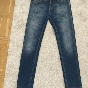 Blå jeans från Tiger of Sweden W29 L30 - Säljer ett par klassiska blå jeans från Tiger of Sweden. Jeansen har en smal passform med raka ben och snygga slitningar framtill. Perfekta för dig som gillar stilrena och tidlösa jeans med modern känsla.