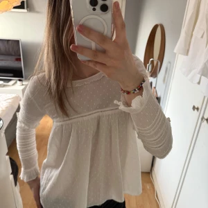 Vit blus från Zara Trafaluc - Säljer en söt vit blus från Zara Trafaluc med fina volangdetaljer på ärmarna. Blusen har lång ärm och är i ett lätt och luftigt material. Perfekt för vår och sommar! Superfint skick!💕