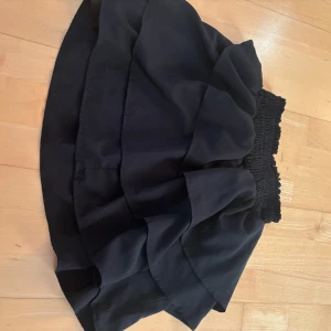 Svart volangkjol från H&M - Säljer en svart kort volangkjol från H&M med bred resår i midjan. Kjolen har flera lager volanger som ger en snygg och puffig siluett. Perfekt att styla med en enkel topp eller stickad tröja. Supersöt! Den är i storlek 145/512, men skulle säga att den passar som xs-xxs. ALLTID 10% RABATT NÄR DU KÖPER 2 PLAGG ELLER FLER💗🫶!!!