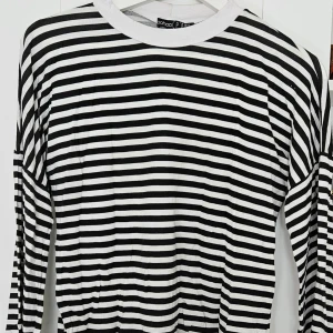 Svartvit randig långärmad tröja från Boohoo - Säljer en svartvit långärmad tröja från Boohoo med klassiskt horisontellt randigt mönster. Tröjan har rund halsringning med vit kant och är i mjuk bomull. Perfekt för en stilren och avslappnad look.