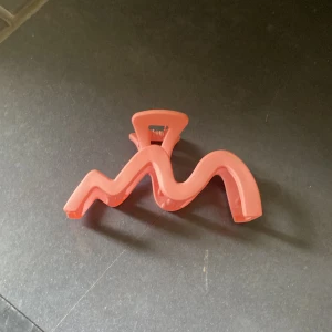 Rosa hårklämma i vågig form - Säljer en cool rosa hårklämma med vågig design. Har använts 1 gång!