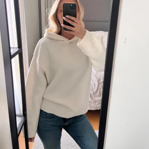 Vit stickad hoodie - Mysig vit stickad hoodie med luva och långa ärmar. Tröjan har en avslappnad passform och ribbade muddar vid ärmslut och nederkant. Inga defekter. Storlek S