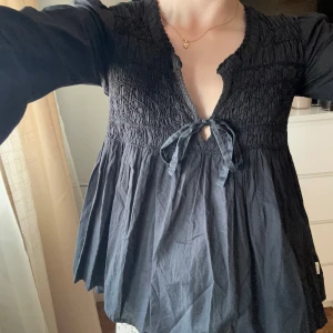 Svart blus odd Molly  - Säljer en svart blus med smock upptill och v-ringning. Blusen har långa ärmar och ett dekorativt knyt framtill under bysten. Modellen är luftig och har en lätt utställd passform. Storlek 1 så ca xs/s💞
