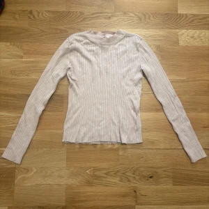 Ljusrosa ribbad tröja från H&M Divided - Säljer en ljusrosa ribbad långärmad tröja från H&M Divided. Tröjan har en enkel och stilren design med rund halsringning och smal passform. Perfekt att matcha med jeans eller kjol.