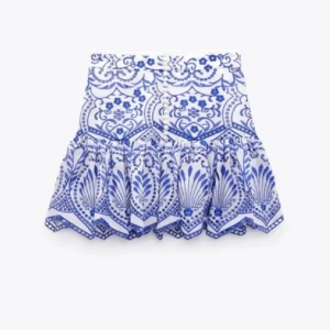 Vit och blå mönstrad kjol från Zara - Supersnygg kort kjol från Zara med blått och vitt mönster och volang nertill. Kjolen har dekorativa knappar framtill och är perfekt för sommarens alla tillfällen. Materialet känns lätt och luftigt. Storlek M och har aldrig använts💕☺️