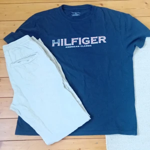 Mörkblå t-shirt från Tommy Hilfiger - Snygg mörkblå t-shirt från Tommy Hilfiger med stort tryck 'HILFIGER American Classic' på bröstet. Klassisk passform och rund halsringning. Perfekt för en avslappnad stil. Storlek S men passar som M