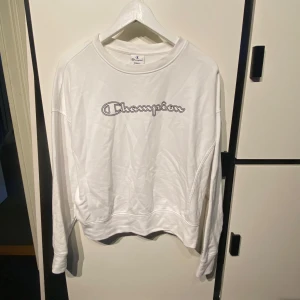 Vit långärmad sweatshirt från Champion - Säljer en vit långärmad sweatshirt från Champion med logga broderad framtill. Tröjan har en klassisk passform och är tillverkad i mjukt bomullsmaterial. Perfekt för en avslappnad och sportig stil.