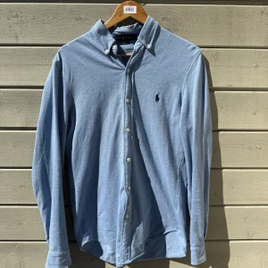 Ljusblå skjorta från Ralph Lauren - Säljer en klassisk ljusblå skjorta från Ralph Lauren i modellen Featherweight Mesh. Skjortan har långa ärmar, knappar framtill och button-down krage. Perfekt för dig som gillar stilrena och tidlösa plagg. Steal!!!! Sitter som M