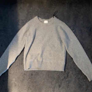Grå stickad tröja från H&M XS - Mysig grå stickad tröja från H&M i storlek XS. Tröjan har rund hals, ribbade muddar vid ärmslut och nederkant samt långärmade ärmar. Perfekt för kyliga dagar och enkel att matcha med jeans. Tröjan är fläckfri och har bara använts några gånger. Den är basically ny och har inga nopprar.