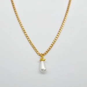 Guldhalsband med pärlhänge - Stilrent halsband i guldton med en kedja och ett droppformat vitt pärlhänge som har en liten guldfärgad detalj upptill. Perfekt för dig som gillar klassiska smycken med en modern twist. Kedjan har ett smidigt lås och passar till många olika looks.