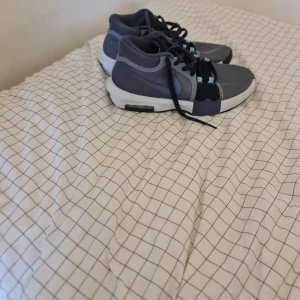 Nike sneakers blå/grå strl 43 - Nike sneakers i storlek 43 med snygg design i mörkblått och grått. Skorna har mesh-ovandel, vita och svarta detaljer på sulan samt ljusblå öglor för snörningen. Perfekta för dig som gillar sportig stil och vill ha bekväma skor med cool look.lebrons nike performence wittness