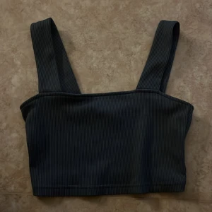 Svart ribbad linnetopp från H&M Divided - Snygg svart linnetopp från H&M Divided i storlek S. Toppen har breda axelband och är ribbad för en cool struktur. Croppad passform som sitter tajt och ger en modern vibe. Perfekt att styla med jeans eller kjol för en chill look.