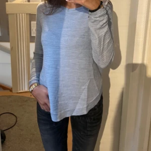 Ljusblå stickad tröja med slits - Säljer en ljusblå stickad tröja med diskret randigt mönster. Tröjan har lång ärm och en snygg slits på sidan som ger en chill vibe. Perfekt att matcha med jeans eller leggings. Mjuk och skön, passar dig som gillar enkel men stilren look.