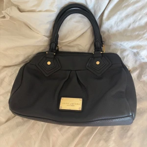 Svart handväska från Marc Jacobs med guld bricka  - Snyggaste Marc Jacobs väskan!! 8/10 skick, endast ett par repor på guld brickan