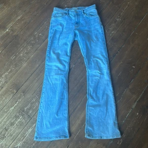 Bootcut ljusblå jeans från Gina Tricot - Säljer ett par ljusblå bootcut jeans från Gina Tricot, modell Perfect Jeans. De har klassisk femficksdesign, normal passform upptill och snyggt utsvängda ben. Jeansen är tillverkade i mjukt denimtyg och har midwaist. Perfekt för dig som gillar retrovibbar och bekväm stil.