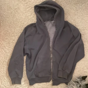 Mörkgrå hoodie från Brandy Melville - Säljer en mörkgrå hoodie från Brandy Melville med dragkedja och huva. Tröjan har långa ärmar, två fickor fram och är gjord i mjuk bomull med fleece på insidan. Perfekt för chill dagar och enkel att matcha med jeans eller leggings.