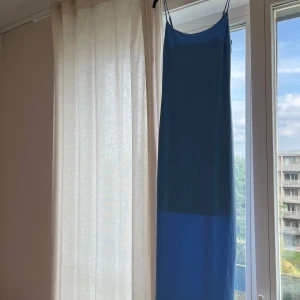Blå långklänning från Bik Bok - Säljer en stilren blå långklänning från Bik Bok i storlek S. Klänningen har smala axelband och en rak, enkel siluett som ger en clean look. Materialet är mjukt och känns lätt mot huden, perfekt för varma dagar. Färgen är klarblå och ger en fräsch vibe. Som man kan se på första bilden finns det ett tyg inuti som ger en tjockare känsla av materialet och skyddar mot att se konturer och mot genomskinlighet. 