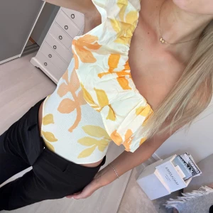 off-shoulder body med volang  - Superfin off-shoulder body från zara med volang upptill och blommigt mönster i gult och oranget. Storlek S, helt ny med lappen kvar!!