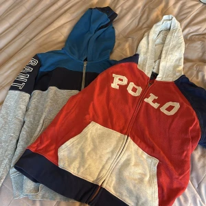 Två hoodies från Polo Ralph Lauren & GANT - Säljer två snygga hoodies! En Polo Ralph Lauren med röd, grå och marinblå färgblock, stor ficka fram och vit POLO-tryck. Den andra från GANT har blå, marinblå och grå färgblock med GANT-tryck på ärmen. Båda har huva och dragkedja. Priset kan diskutera