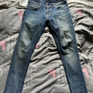 Nudie Jeans - Säljer ett par blå skinny jeans från Nudie Jeans i storlek W31 L30. Klassisk femficksmodell med orangea sömmar och Nudie-logga på bakfickan. Jeansen har en smal passform och är tillverkade i slitstarkt denim med snygg tvättad look. Hör av er i dm ifall ni har några frågor!😃