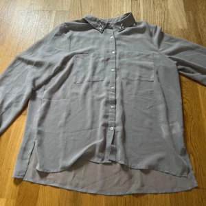 Grå blus med pärldetaljer från H&M - Säljer nu denna jättefina blus då den aldrig kommit till användning!🩷Använd max 2 gånger så den är i väldigt fint skick!🩷 Önskas fler bilder eller om man har några frågor så är de bara att höra av sig!🩷