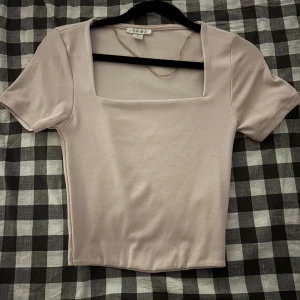 Ljusbeige topp  - Säljer en ljusbeige topp från Amisu med snygg fyrkantig halsringning och korta ärmar. Modellen är croppad och har en slim passform som sitter snyggt. 