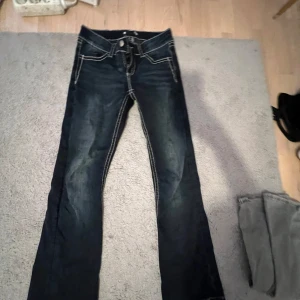 Mörkblå jeans med broderade fickor från Gina tricot - Säljer ett par mörkblå jeans med snygga kontrastsömmar och broderade detaljer på bakfickorna. Dem är bootcut och har använt bara några gånger