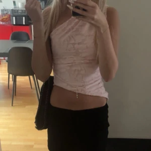 Ljusrosa oneshoulder topp - Säljer en ljusrosa oneshoulder topp med croppad passform. Toppen har ett subtilt mönster och är figurnära, perfekt för dig som gillar trendiga och unika plagg. Materialet känns mjukt och lätt mot huden.