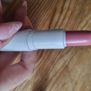 Indy Beauty rosa satin läppstift - Snyggt rosa satinläppstift från Indy Beauty, 100% veganskt och med mjuk finish. Kommer i en vit, stilren hylsa med rosa text. Perfekt för dig som vill ha en naturlig men ändå fräsch look med lite extra glans.