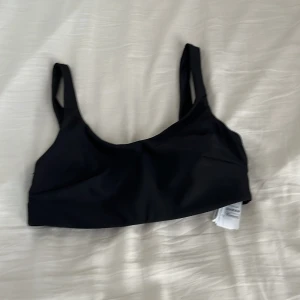 Svart bikiniöverdel från Esmara - Svart bikiniöverdel från Esmara i stilren och enkel design. Modellen har breda axelband och en rak, sportig form som ger bra stöd. Materialet är mjukt och stretchigt syntet, perfekt för strandhäng eller poolen. Passar dig som gillar minimalistisk stil.