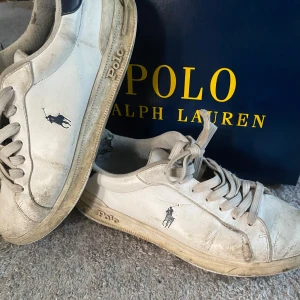 Vita sneakers från Polo Ralph Lauren - Snygga vita sneakers från Polo Ralph Lauren med klassisk logga på sidan. Skorna har rund tå, platt sula och snörning. Ovandelen är i 100% skinn, fodret i textil och yttersulan i gummi. Perfekt för dig som gillar stilrena och tidlösa sneakers.