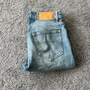 Ljusblå jeans Pistolero 29/32 - Snygga ljusblå jeans från tiger of Sweden,Pistolero, med klassisk femficksdesign och raka ben. Jeansen har en cool tvättad look och detaljer med kontrastsömmar. Passar dig som gillar en avslappnad stil med lite vintagekänsla.