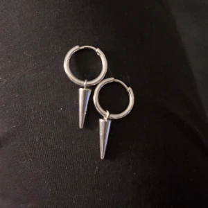 Silverörhängen med spetsiga hängen - Coola örhängen i silverfärg från Vince med runda hoops och spetsiga konformade hängen. Perfekta för dig som gillar edgy och minimalistisk stil. Snygga att bära både ensamma eller tillsammans med andra smycken för en personlig look.