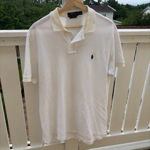 Vit pikétröja Ralph Lauren - Vit pikétröja från Ralph Lauren i modellen Custom Slim Fit. Klassisk krage, korta ärmar och broderad logga på bröstet. Tillverkad i bomull. Hör av dig vid några frågor!