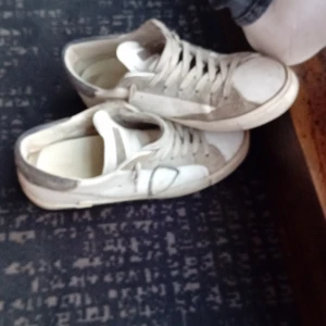 Vita sneakers med grå detaljer - Snygga vita sneakers med grå detaljer och klassisk snörning. Skorna har en platt sula i gummi och rund tå. Perfekta för en avslappnad streetstyle-look. Materialet är troligtvis syntet och skinn.