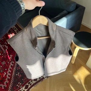 Sothiares väst - Snygg brun väst från Sothiares i ullblandning med dragkedja framtill. Helt ny. Västen har en stilren, rak passform och hög krage med diskret broderad logga i nacken. Perfekt lager-på-lager-plagg, helt slutsåld på deras hemsida, reversable så går att ha åt båda hållen, riktigt snygg och unik!