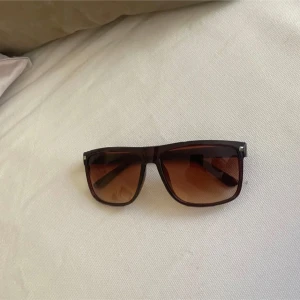 Bruna fyrkantiga solglasögon - Snygga solglasögon med fyrkantig form och brunt transparent plastbåge. Glasen är tonade i brunt och ger en cool vibe till din look. Perfekta för soliga dagar och en stilren touch till outfiten. Liknar rayban