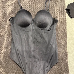 Svart korsettbody, 80B - Säljer en svart korsettbody med Justerbara axelband och smickrande passform. Snyggt stretchigt material som ger en tight siluett. Perfekt att styla under en kavaj eller till jeans för en trendig look. Ingen push up!!!